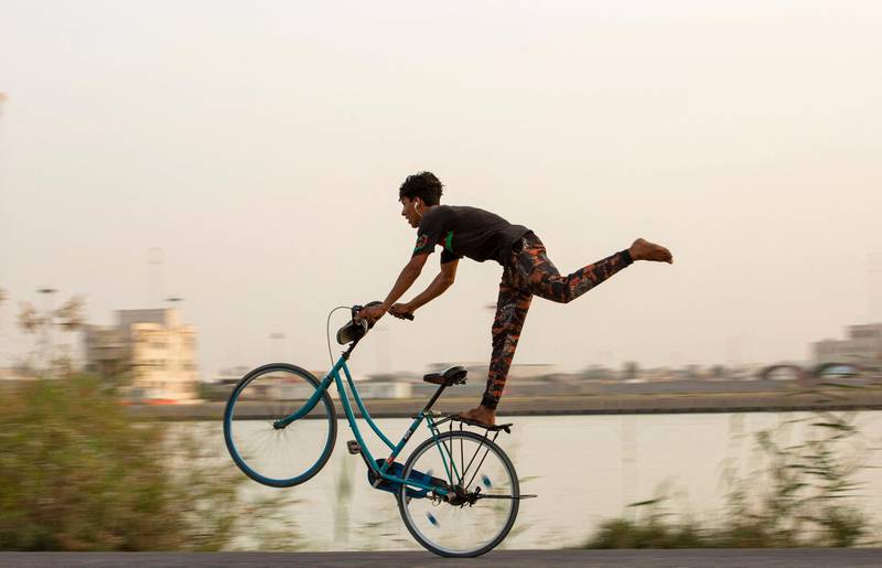 A youth shows off his balancing skills as he performs stunts on a bicycle, on the bank of the Shatt Al-Arab river at sunset, in the southern Iraqi city of Basra. AFP