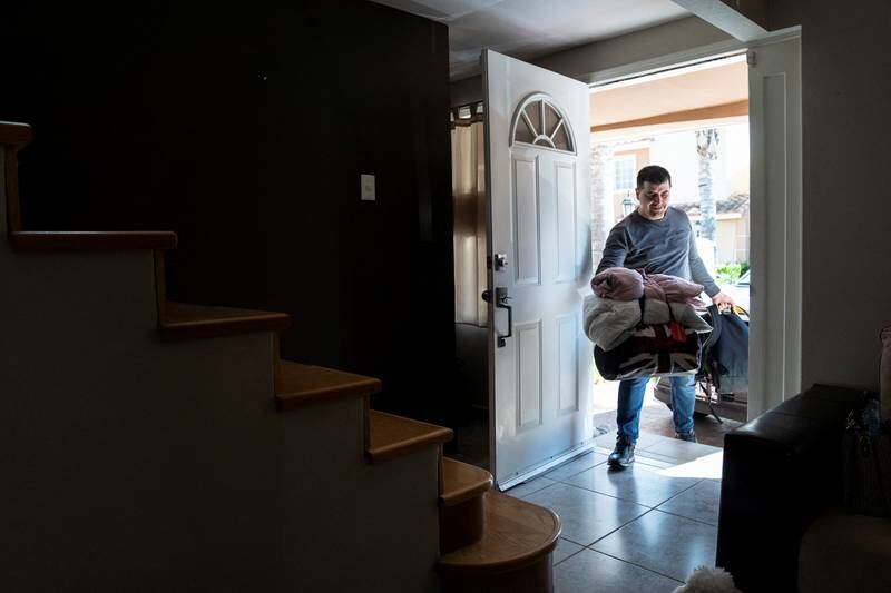 Petro Nazarii, 39, carries luggage into the house of a family temporarily hosting his family in Tijuana, Mexico, as they wait to enter the US. Reuters