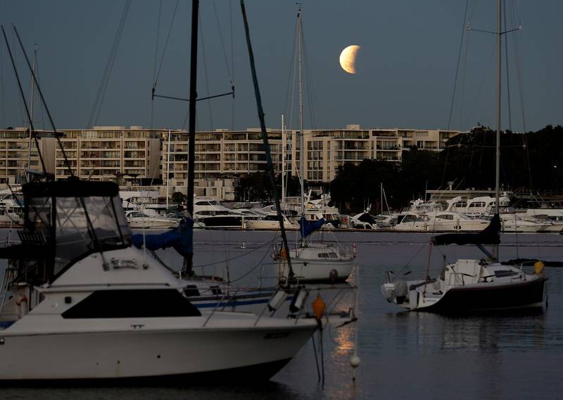 The moon begins to set over Sydney harbour during the eclipse in Australia. AP Photo/Rick Rycroft