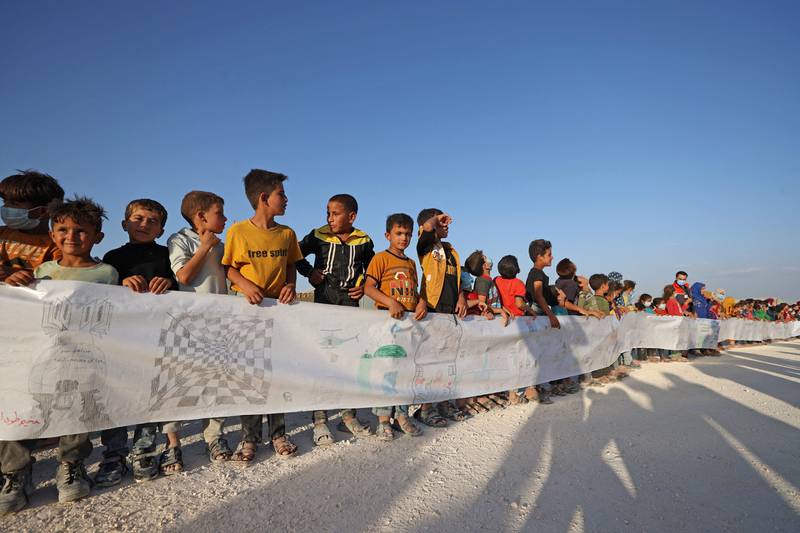 Syrian children hold a paper roll with their drawings and messages during an event origanized by the Shafak NGO marking the International Day of Peace at a camp for internally displaced people (IDP) in the town of Maarrat Misrin in Syria’s northwestern Idlib province. The International Day of Peace, also known as World Peace Day, is observed every year on September 21.