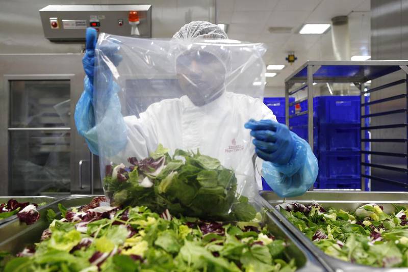 A member of the catering staff packs individual bags of salad so that cabin crew can easily plate fresh salad on to passengers' plates. Antonie Robertson / The National