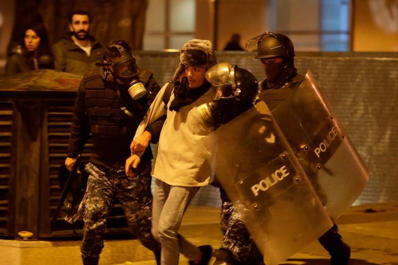 Riot police detain an anti-government demonstrator during clashes in the capital Beirut on December 14, 2019. AFP