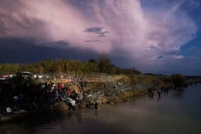 Migrants wait behind razor wire after crossing the Rio Grande as they try to enter the US at Eagle Pass, Texas. Reuters