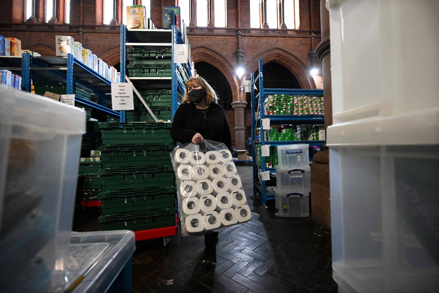 A volunteer stocks shelves with donated items at a food bank in Brixton, south London. Foodbank use is soaring in Britain. AFP