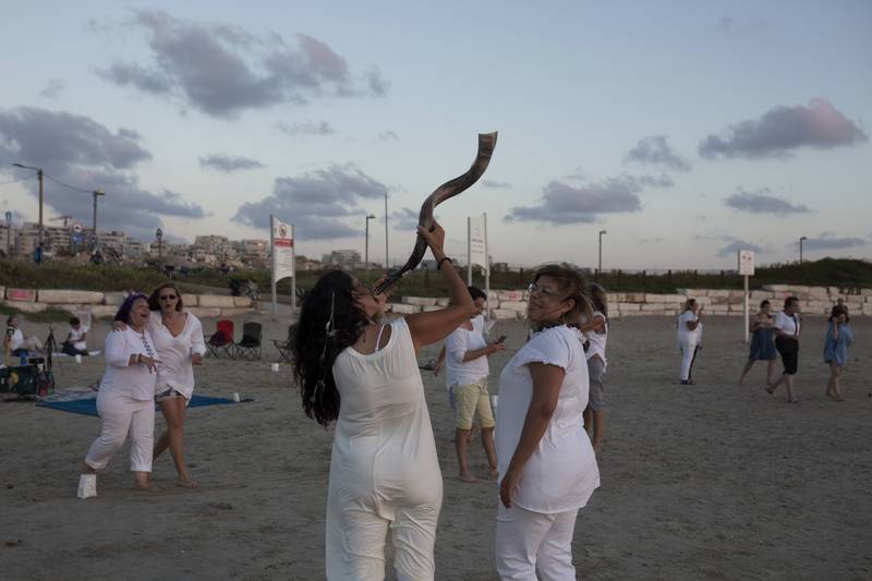 A woman holds a shofar before the start of a Tashlich ceremony, on the beach in Tel Aviv.  AP
