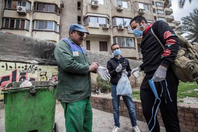 Volunteers distribute masks and gloves to a sanitation worker in a Cairo street. AFP