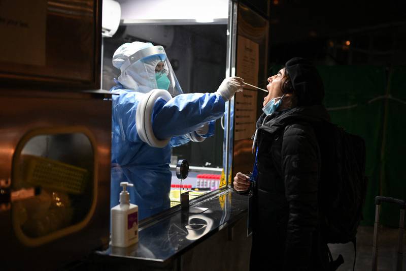 A health worker collects a swab sample from a member of the media before the start of the 2022 Winter Olympics in Beijing. AFP
