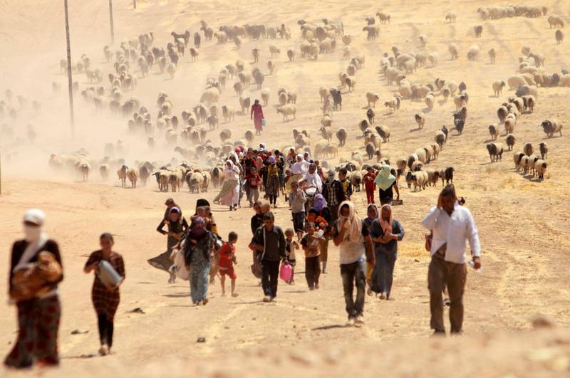 FILE PHOTO - Displaced people from the minority Yazidi sect, fleeing violence from forces loyal to the Islamic State in Sinjar town, walk towards the Syrian border, on the outskirts of Sinjar mountain, near the Syrian border town of Elierbeh of Al-Hasakah governorate, Iraq August 10, 2014. REUTERS/Rodi Said/File Photo