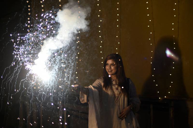 A young woman lights a firecracker as she celebrates Diwali in Karachi. AFP