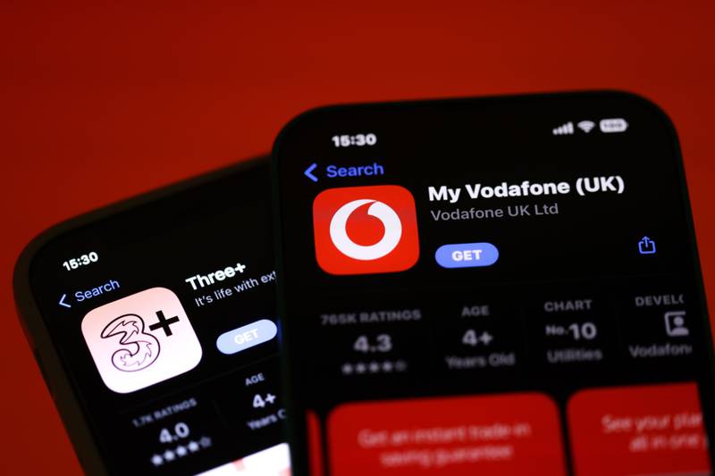 Smartphones display the Three and Vodafone apps on the Apple App Store. Bloomberg