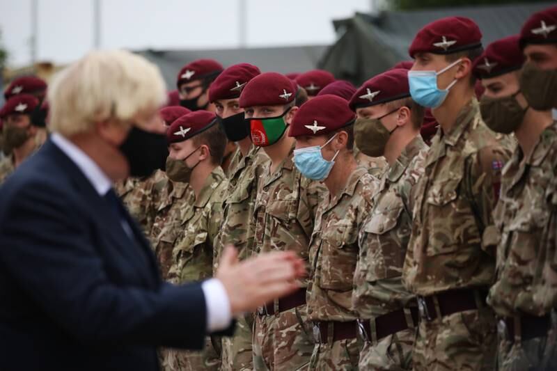 A soldier wearing a protective face mask depicting the flag of Afghanistan looks on as Mr Johnson meets military personnel who worked on the Afghan evacuation during a visit to Merville Barracks on September 2.