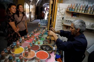 Tourists look on as Palestinian craftsman Mohammed Al-Awawda creates coloured sand artworks at his souvenir shop in Hebron, in the Israeli-occupied West Bank. Reuters
