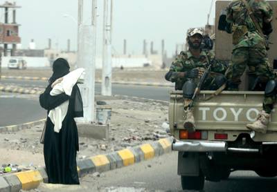 A picture taken on August 9, 2018 during a trip in Yemen organised by the UAE's National Media Council (NMC) shows Yemeni fighters loyal to the Saudi and UAE-backed government driving past a woman carrying a baby on a main road in Yemen's second city of Aden. (Photo by KARIM SAHIB / AFP)