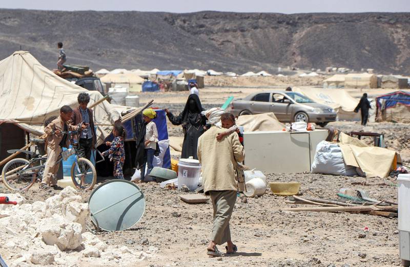 A man walks carrying a child at a camp for internally displaced people about 10 kilometres on the outskirts of Yemen's northeastern city of Marib on March 28, 2021, as residents of the camp prepare to flee due to its proximity with battles between forces of the Huthi-rebels and the Saudi-backed government troops.  / AFP / STR
