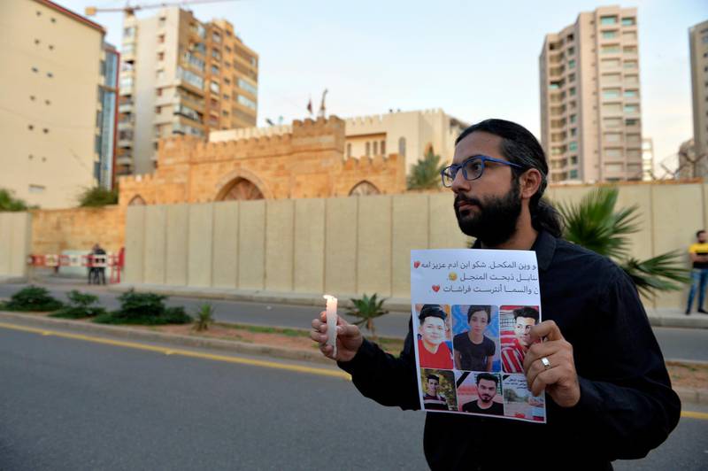 A Lebanese activist carries a candle and a picture for an Iraqi child who died during the uprising in Iraq during a gathering to support the children in the uprising in Iraq in front of the Iraqi embassy in Beirut.  EPA