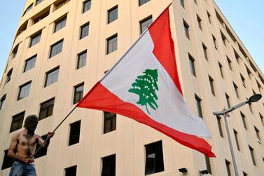  An anti-government protester stands on a concrete wall set up by Lebanese police to block a road leading to the parliament building as he carries a Lebanese flag during a protest in downtown Beirut, Lebanon. EPA