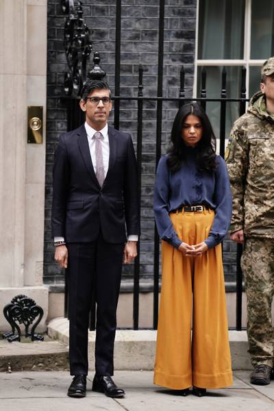 Burnt orange wide-legged trousers paired with a blue flowing blouse outside 10 Downing Street, London