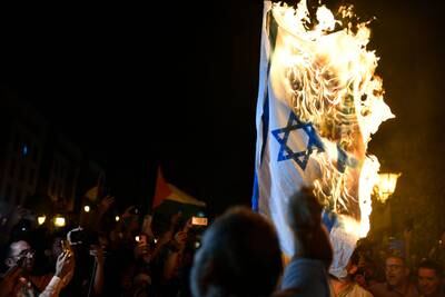 Protesters burn an Israeli flag as they gather in front of Parliament Square. EPA