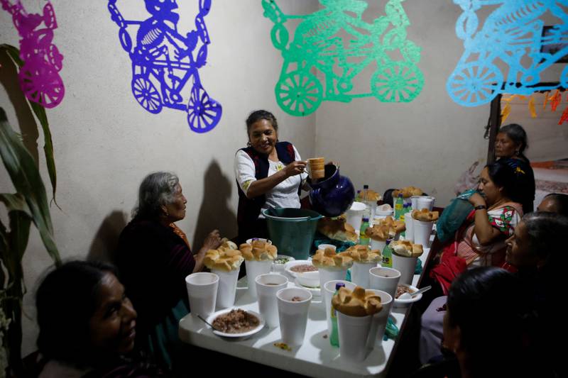 A woman serves food for her guests near an altar in homage to a person who died recently during the annual Day of the Dead celebration in Santa Fe de La Laguna in Mexico. Reuters