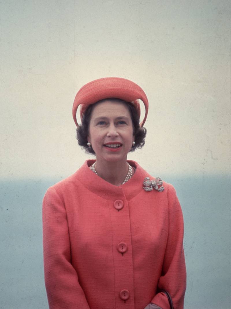Queen Elizabeth II, wearing a red coat and co-ordinated hat, during a royal visit to the Isle of Wight on July 26, 1965. Getty Images