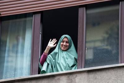 Silvia Romano waves from a window after she arrived at her home, in Milan, Italy.  EPA