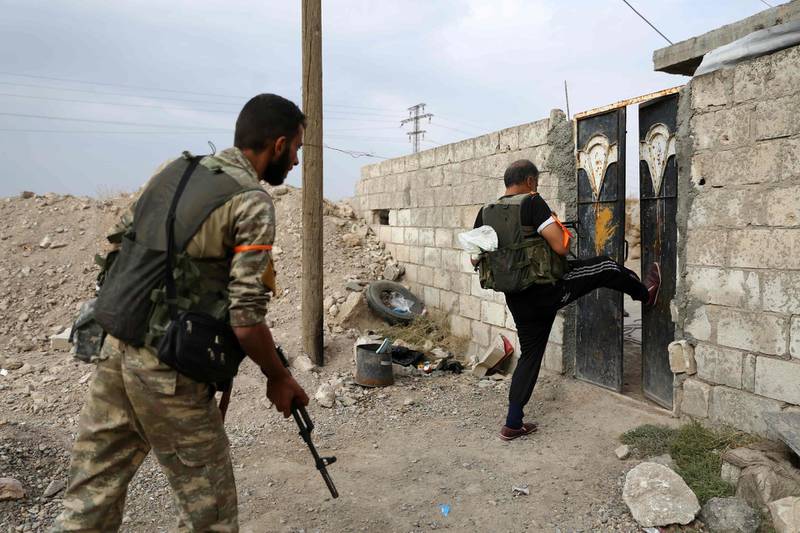 Turkey-backed Syrian fighters break open the front door of a house at a postition that they are holding in the Syrian border town of Ras Al Ain.  AFP