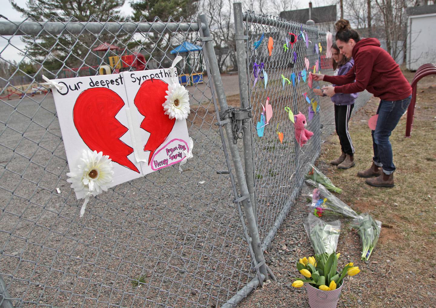  A woman and her daughter place a heart on a fence at a growing memorial in front of the Debert School in Debert, Nova Scotia, after Lisa McCully, a teacher at the school, was killed in a mass shooting.