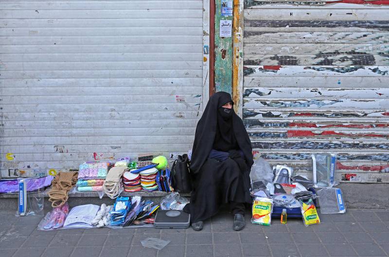 An Iranian street vendor wearing a protective mask amid the novel coronavirus pandemic, sits by her display of goods on a street of the capital Tehran, on May 09, 2020. / AFP / ATTA KENARE
