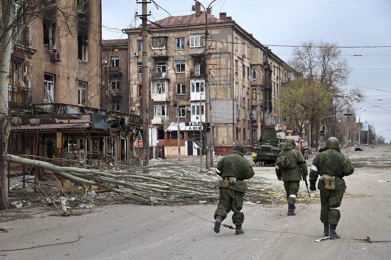Troops walk past damaged buildings in a Russian-controlled part of Mariupol in Ukraine. AP