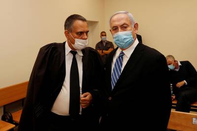 Israeli Prime Minister Benjamin Netanyahu, wearing a mask, stands inside the courtroom as his corruption trial opens at the Jerusalem district court. Reuters