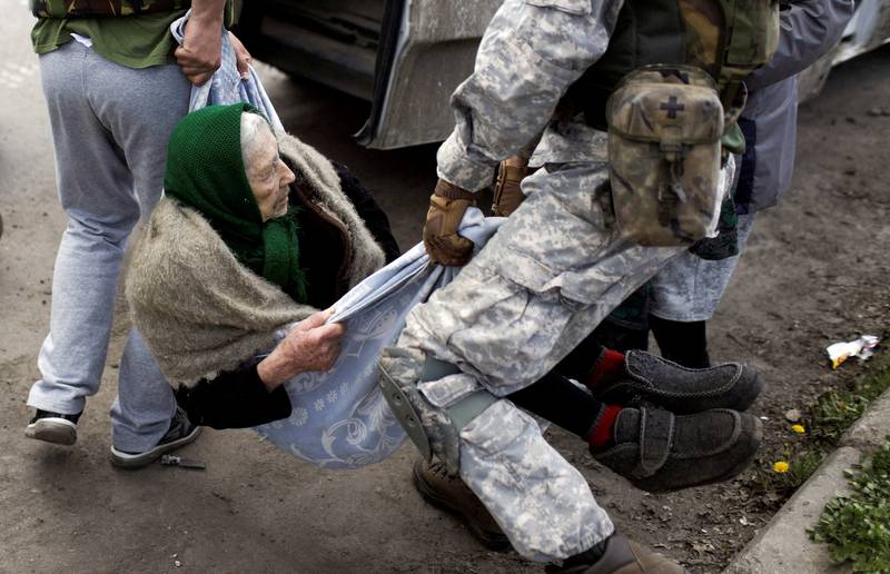 Volunteers carry an elderly woman in a blanket during the evacuation of a frontline village retaken by Ukrainian forces in Kharkiv.  Reuters