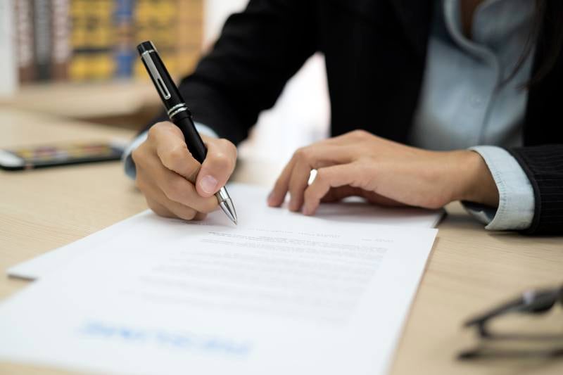 Close up of woman signing contract in job application form. Getty Images
