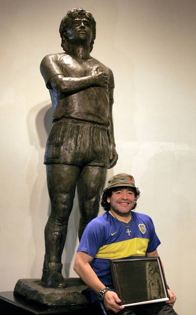 Former soccer star Diego Maradona poses in front of his statue, commissioned as a tribute by a group of fans, at the Boca Juniors Museum (Museo de la Pasion Boquense), in La Bombonera stadium, Buenos Aires, November 26th 2006. The sculpture is 2.2 meters tall and weighs some 300 kilos.  AFP PHOTO/Juan MABROMATA (Photo by JUAN MABROMATA / AFP)