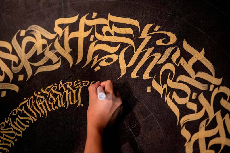 This photo taken on June 22, 2019 shows artist Taipan Lucero doing calligraphy using the indigenous script known as Baybayin, used before Spanish colonisation in 1521, at an event in Manila. From tattoos, shirts, and artworks to a computer font and mobile apps, Baybayin found a rebirth among millennials and professionals learning its 17 characters beyond the marginal mention in history class. 
 - TO GO WITH AFP STORY: Philippines-culture-language, FEATURE by Ayee MACARAIG
 / AFP / Noel CELIS / TO GO WITH AFP STORY: Philippines-culture-language, FEATURE by Ayee MACARAIG
