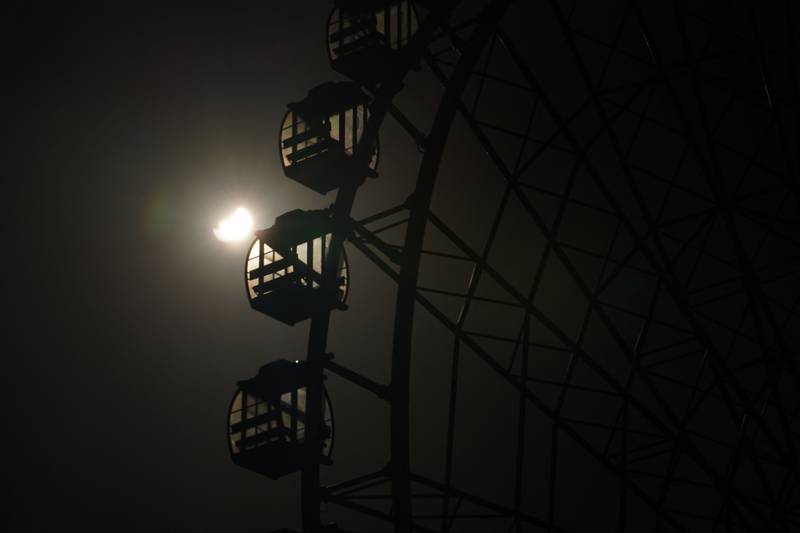 A view of the partial solar eclipse behind the pods of a Ferris wheel at an amusement park in Dohuk in Iraq's autonomous Kurdistan region. AFP