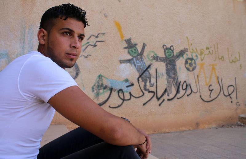 Moawiya Sayasina, the Syrian activist who started scribbling anti-Assad slogans in 2011, sits next to a graffiti drawn on the wall of a schoolyard reading in Arabic "Your turn, Doctor", in a rebel-held neighbourhood in the southern Syrian city of Daraa. Mohamad Abazeed / AFP