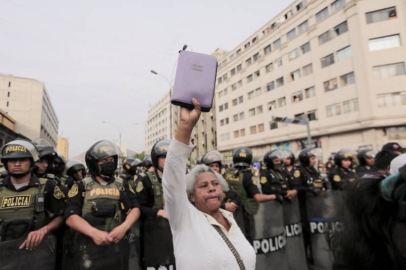 A demonstrator holds up a bible in front of police officers in Lima. Reuters