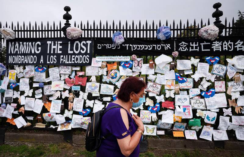 A woman passes a fence outside Brooklyn's Green-Wood Cemetery adorned with tributes to victims of COVID-19 in New York on on May 28, 2020. AP Photo