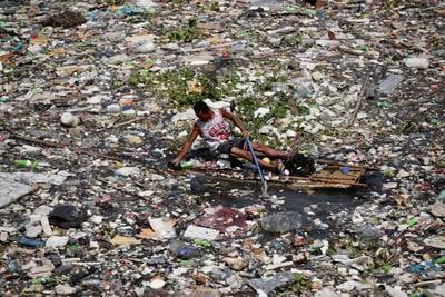 A villager on a makeshift raft collects items washed up near Paranaque city in the Philippines. EPA