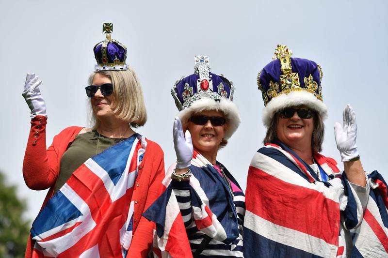 Royal fans bedecked with Union flags and crowns pose for a photograph on the Long Walk in Windsor on May 18, 2018, the day before the Royal wedding.  Britain's Prince Harry and US actress Meghan Markle will marry on May 19 at St George's Chapel in Windsor Castle. / AFP / Ben STANSALL
