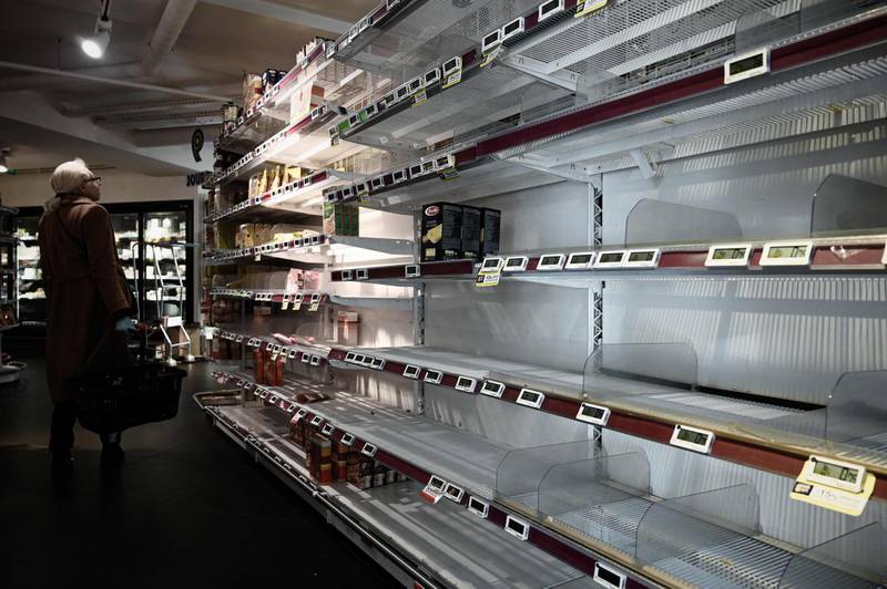 A woman stands next to an empty shelf in a supermarket in Paris a day after France ordered the closure of all non-essential public places including restaurants and cafes.  AFP