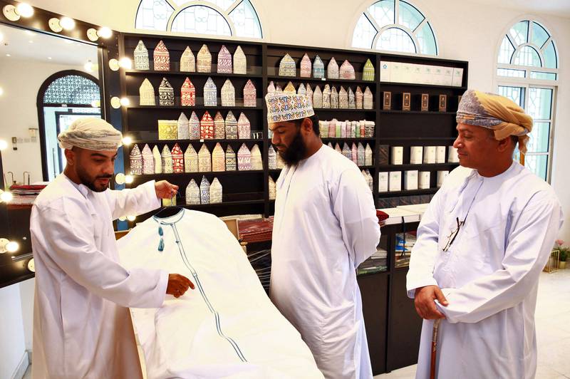 An Omani tailor displays a dishdasha at a shop in the capital Muscat. Foreign imitations and alternative styles have led authorities there to threaten a fine of 1,000 Omani rials ($2,600), or double that in the case of a second violation, for wearing dishdashas that do not adhere to traditional criteria. All photos by AFP