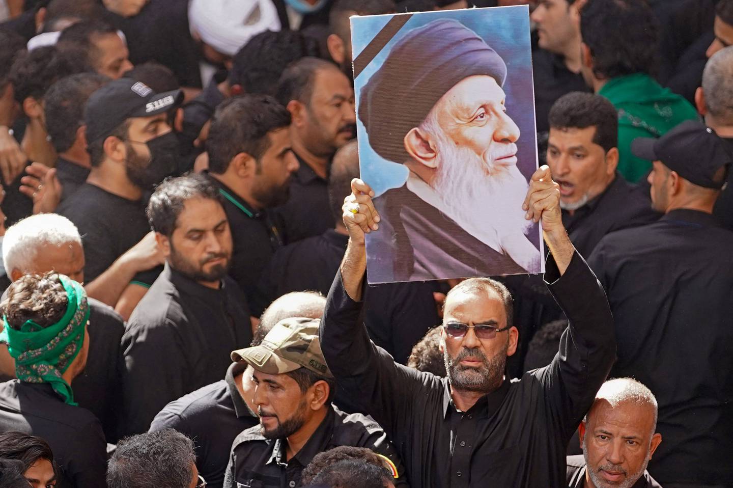 An Iraqi mourner carries a poster of Grand Ayatollah Mohammed Saeed Al Hakim during his funeral.  AFP