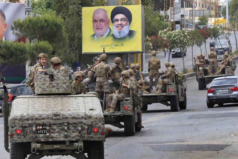 The Lebanese army patrols past a poster showing portraits of Hezbollah leader Hassan Nasrallah, right, and the head of Hezbollah's parliamentary bloc, Mohammed Raad, in Nabatiyeh. AP