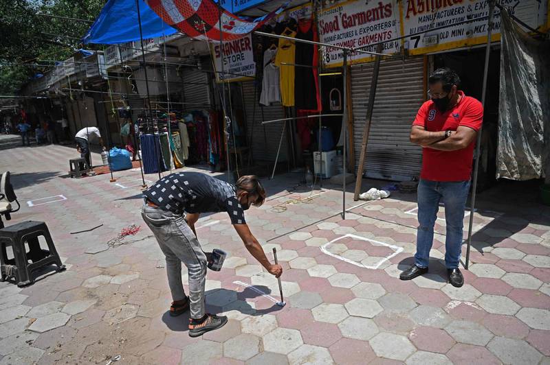 A shopkeeper paints a social distancing mark outside his shop after shops were allowed to reopen with restrictions in New Delhi.