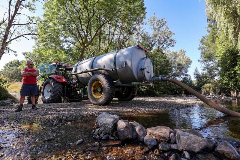 A farmer pumps water in a river near Wellin, southern Belgium. EPA