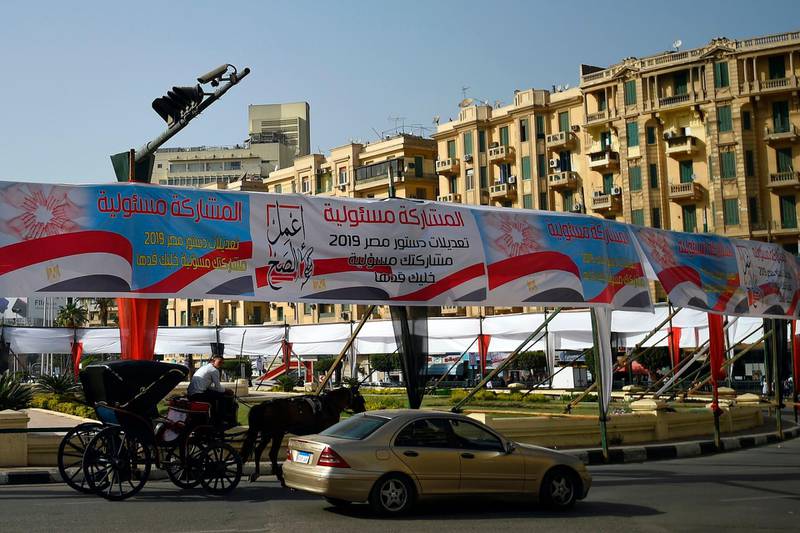 Egyptians pass under banners reading in Arabic "Do what is right", and "Participation is your responsibility", urging voters to participate in the upcoming referendum for the constitutional amendments, in Cairo, on April 08, 2019. Egypt, on April 17, set a referendum for April 20-22 on sweeping consitutional changes including amendments that could extend President Abdel Fattah al-Sisi's rule until 2030. / AFP / Mohamed el-Shahed

