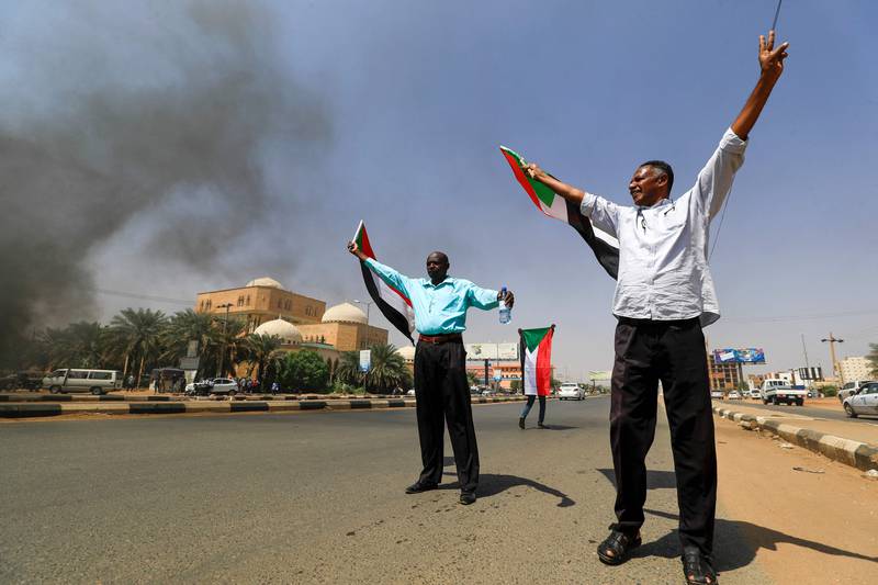 Sudanese men wave national flags as protesters take to the streets of the capital Khartoum to demand a transition to civilian rule.