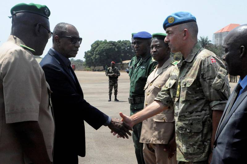 Guinea's President Alpha Conde (L) shakes hand with Head of the UN mission in Mali (Minusma) Danish commanding officer General Michael Lollesgaard (R) at the Conakry airport on February 17, 2016 during the repatriation of the bodies of UN peacekeepers killed in an Islamist attack on their base in Mali. - Seven peacekeepers were initially killed and at least 30 wounded in the early morning assault on the camp belonging to the UN force, known by the acronym MINUSMA, on February 12 in the northeastern town of Kidal. All seven killed were Guinean, three of them women, the source confirmed, representing the first female members of the mission killed in Mali. The MINUSMA mission, launched in July 2013, has been the most deadly for the UN since a deployment to Somalia during the civil war between 1993 and 1995. (Photo by CELLOU BINANI / AFP)
