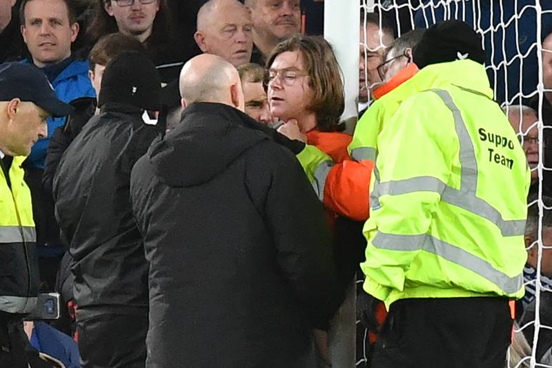 Stewards attempt to release Louis McKechnie, an activist from Just Stop Oil, who attached himself to the goalpost during a football match in Liverpool. AFP